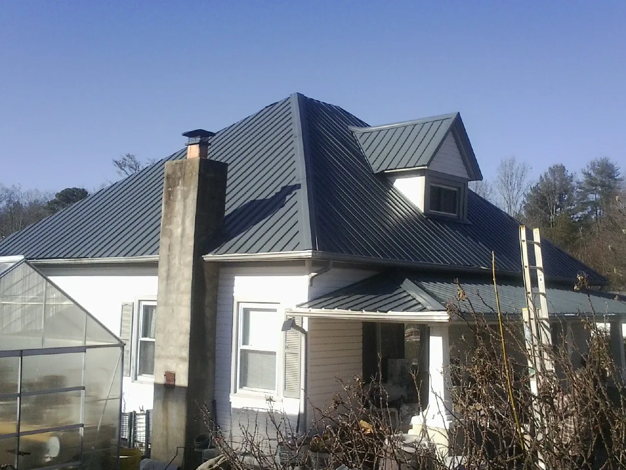 Dark blue standing seam metal roof on a white farmhouse with dormer — Slate & Tile Roof Repair by Roofing Brothers in Severna Park