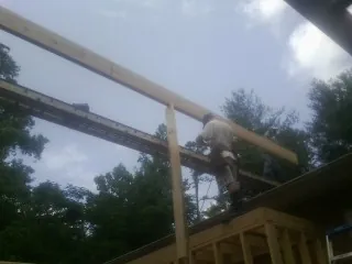 Carpenter setting a ridge beam over a new addition frame — Ice Dam Removal by Roofing Brothers in Severna Park