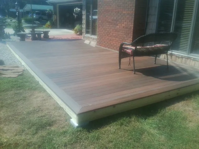 New wood deck and wicker chair beside a brick house in Severna Park