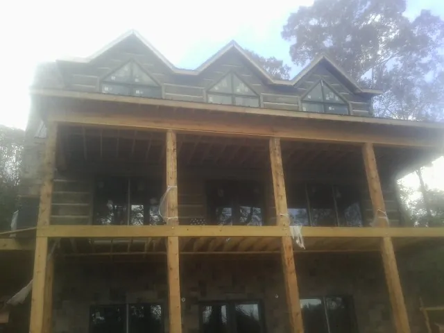 Dormers and porch framing on a large log home under construction — Roof Coating work by our crew in Severna Park