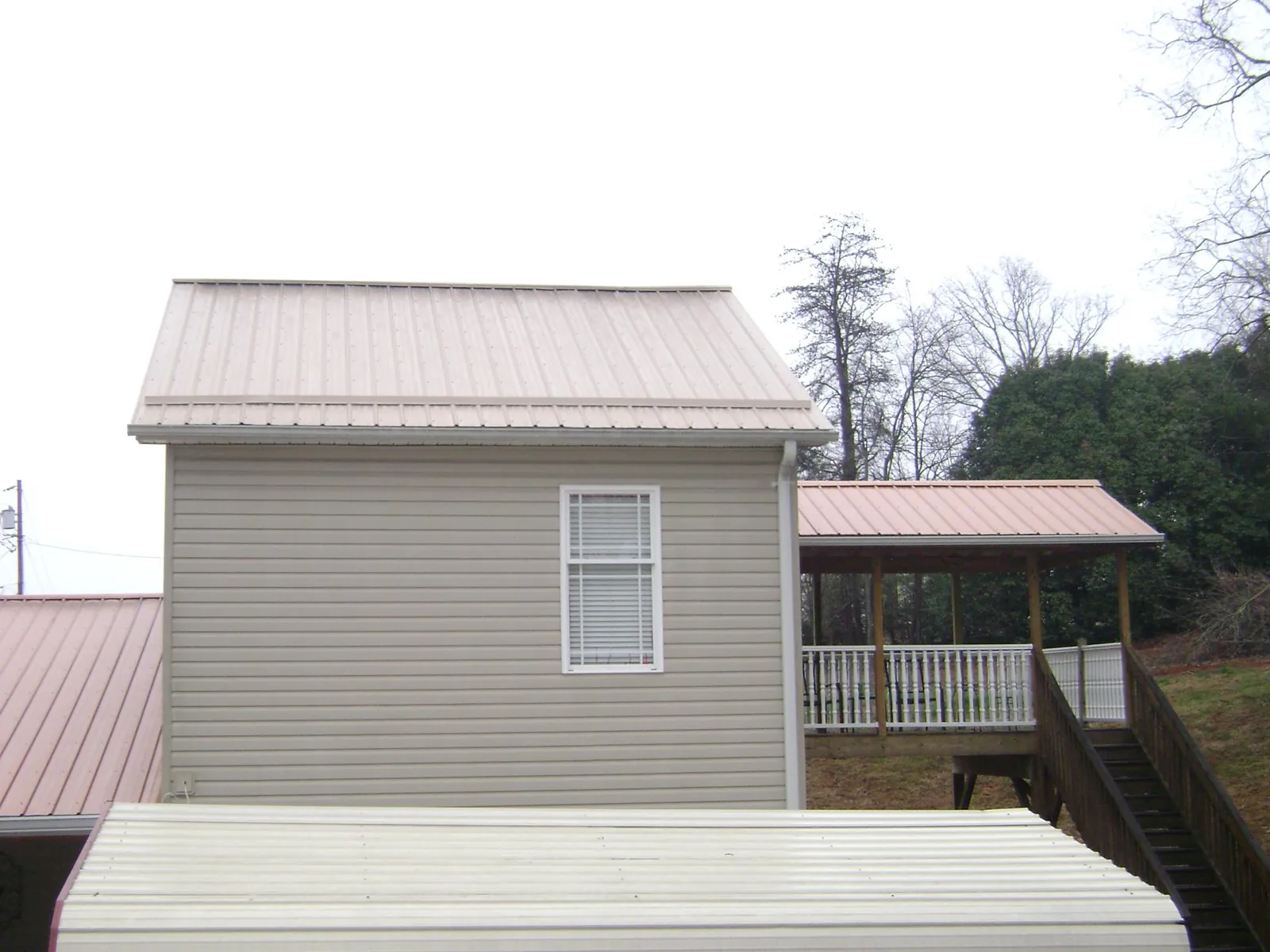 Tan metal roofs on a two story addition and attached porch, from a Roof Replacement job in Severna Park