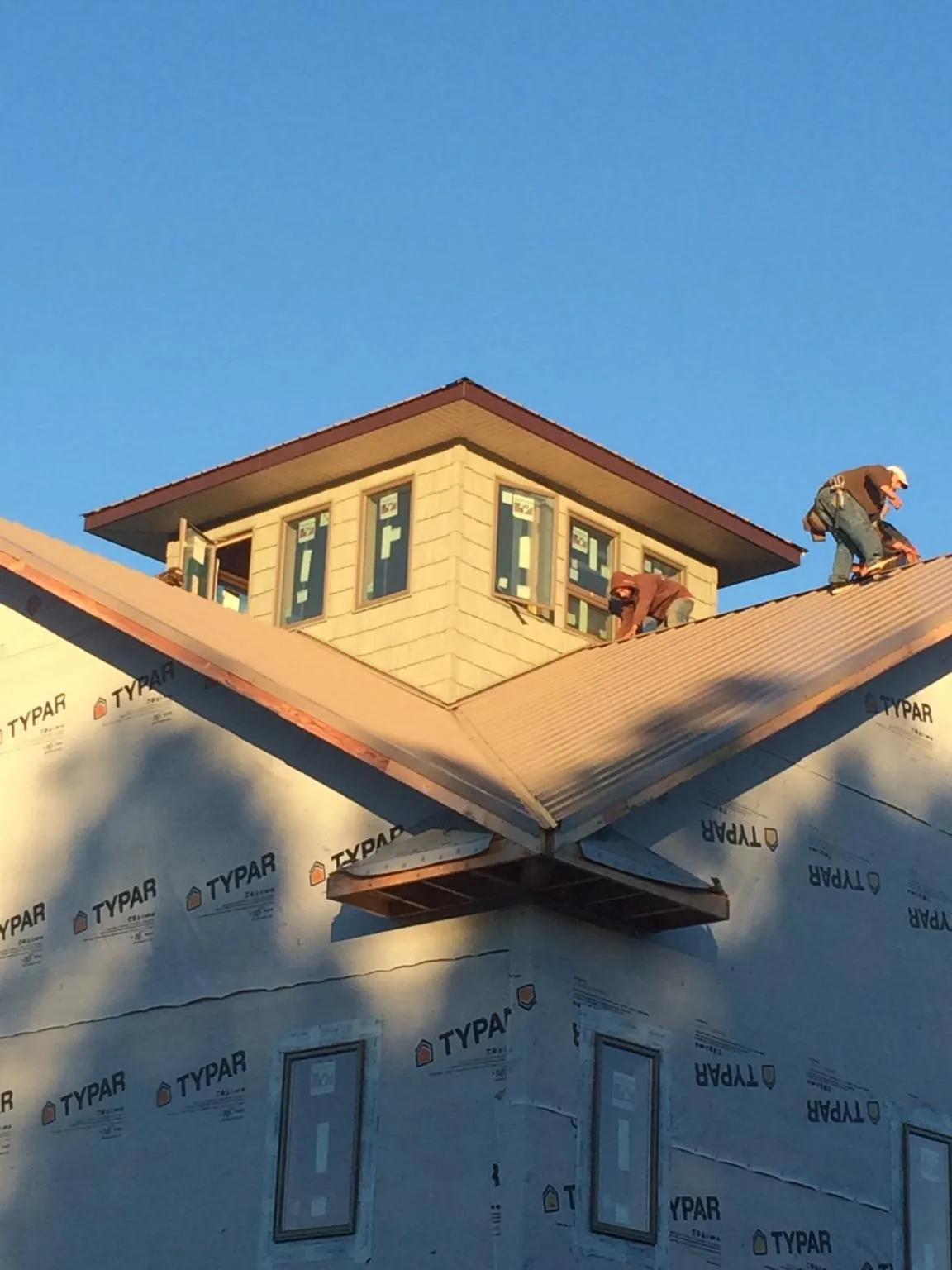 Roofers working around a rooftop cupola on a new metal roof at sunset — Roof Waterproofing in Severna Park by Roofing Brothers